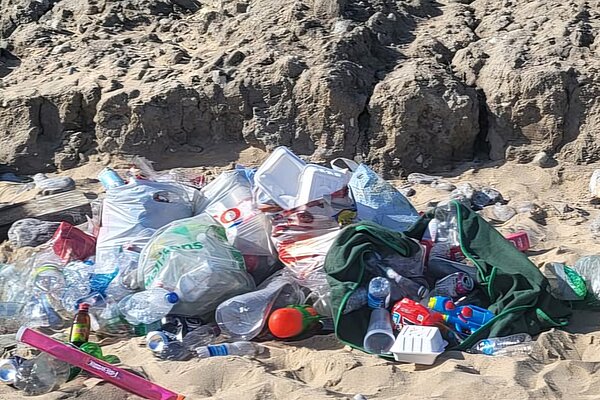 A collection of plastic bottles and rubbish in bags on a beach