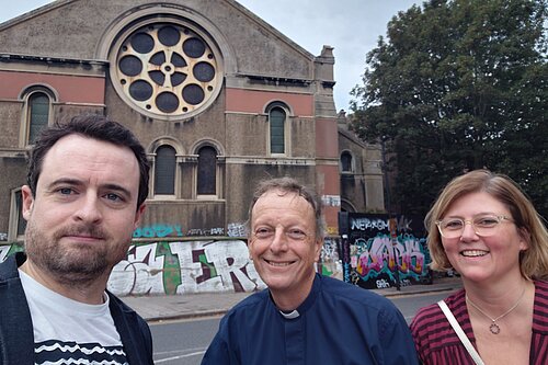Two men and a woman by a church