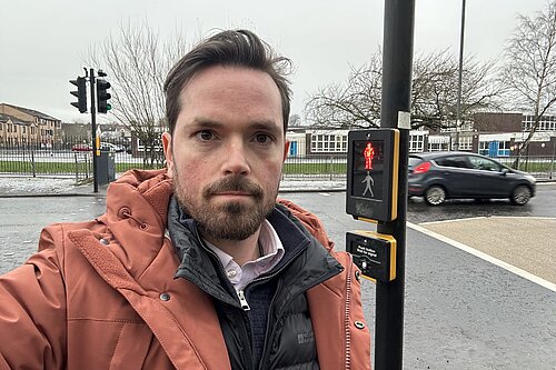 Adam Harley standing at a busy road where crossing patrollers were removed.