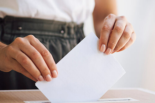 A person putting a ballot paper into a ballot box