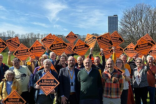 Ed Davey with members of Newcastle Lib Dems holding up Liberal Democrat orange diamond placards